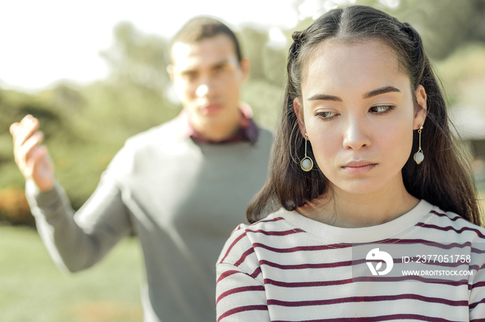 Upset dark-haired woman being tired of her jealous boyfriend