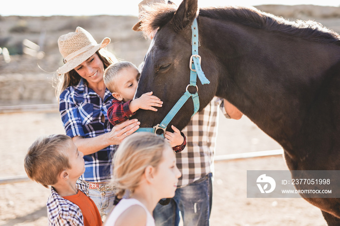 Family enjoy day at horse ranch - Parents and children, family day - Cute little boy kissing a horse