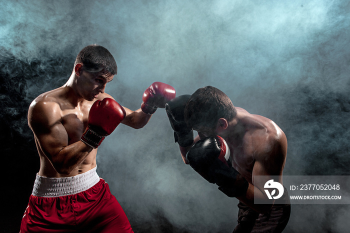 Two professional boxer boxing on black smoky background,