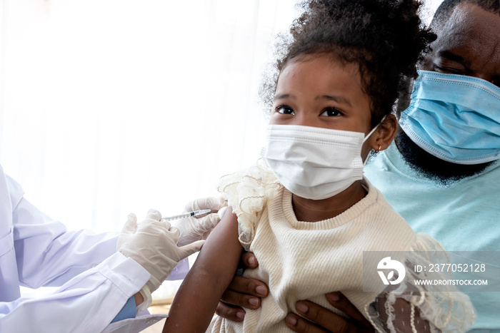 A 5-year-old African-American girl, wearing a surgical mask, whose father was vaccinated for prevent virus from COVID-19 and flu, to people health care and vaccine concept.