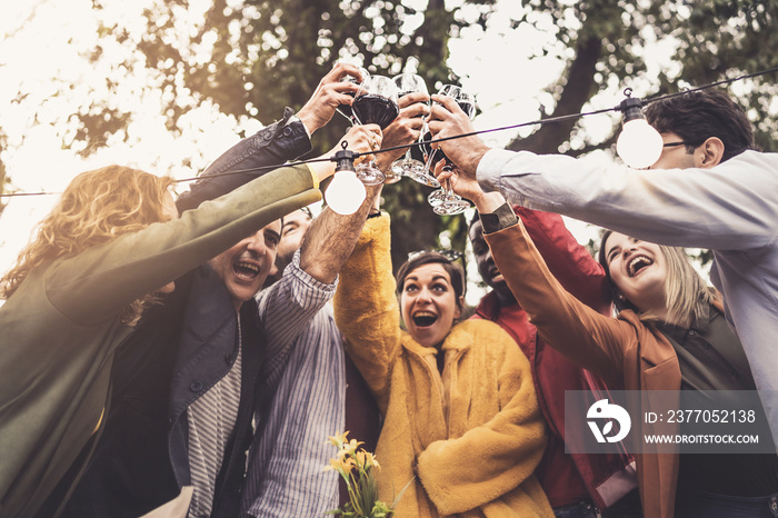 A group of friends of different ethnic backgrounds meet at sunset in the countryside to toast together on the terrace of the farmhouse restaurant - people drinking lifestyle concept - vintage filter