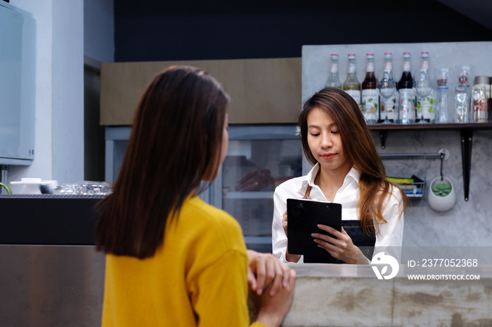 Young asian woman barista taking note, order, at coffee cafe counter with smiling face, food and drink business concept