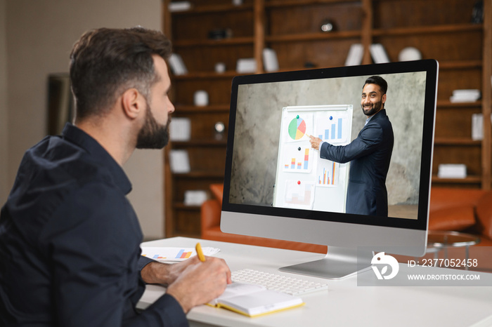 Virtual conference. Young man wearing headset using pc for video call, having video meeting with several people together. Remote work concept