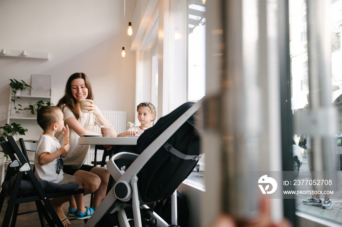 Mother with children drinking hot chocolate and latte at a local coffee shop. They are smiling and having fun. Motherhood concept