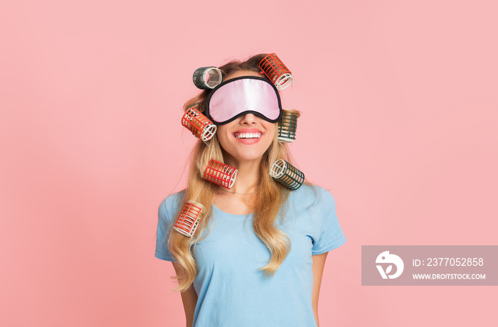 Happy housewife in curlers and mask for sleep