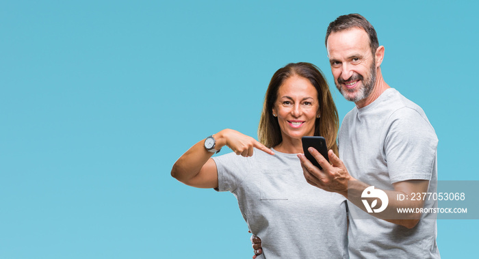 Middle age hispanic couple texting message on smartphone ver isolated background with surprise face pointing finger to himself