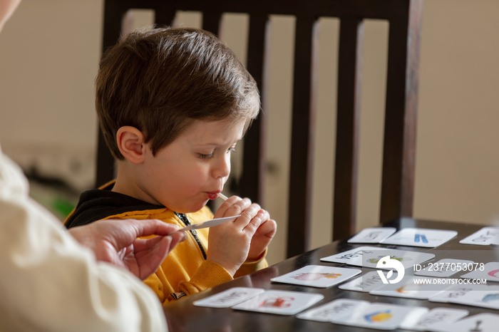 little boy learns words from cards under the ABA therapy program at home at the table