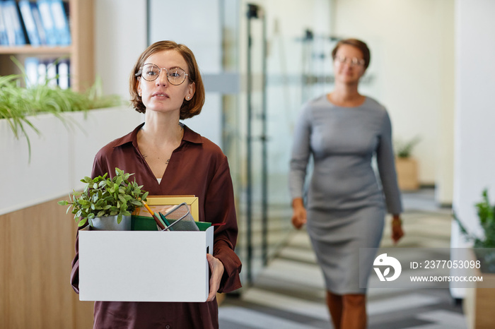 Waist up portrait of young woman carrying box of personal belongings at new job, copy space