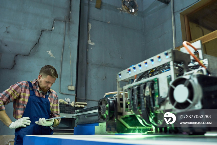 Modern laser engraving equipment in industrial workshop, machine processing glass with operator in background, copy space