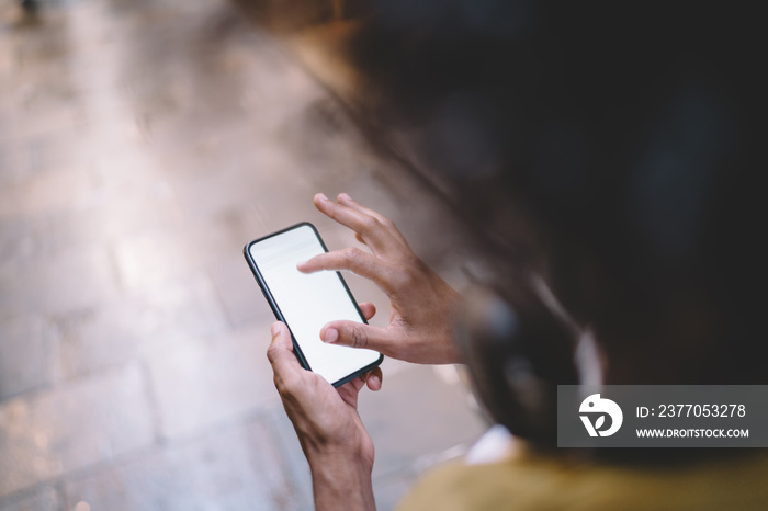 Cropped image of man holding smartphone with blank monitor using navigation application for searching locations, top view of male holding mobile phone checking news and videos from social networks