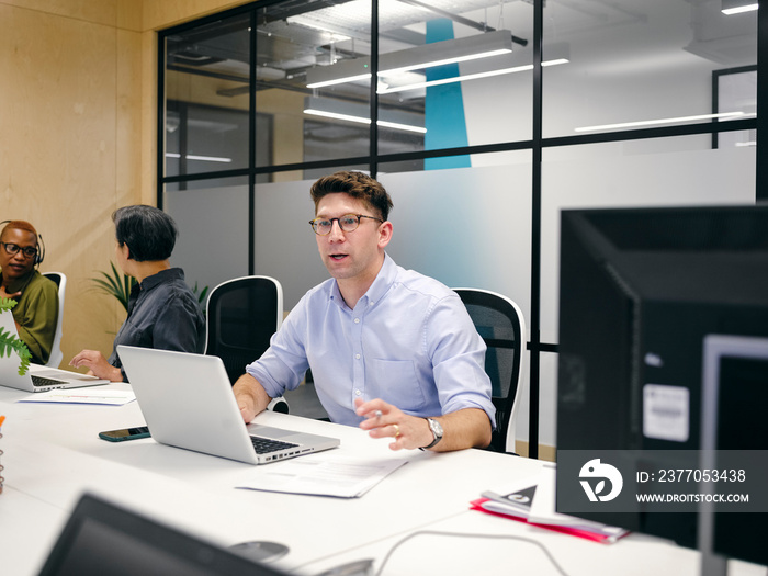 Office workers using computers in co-working office space