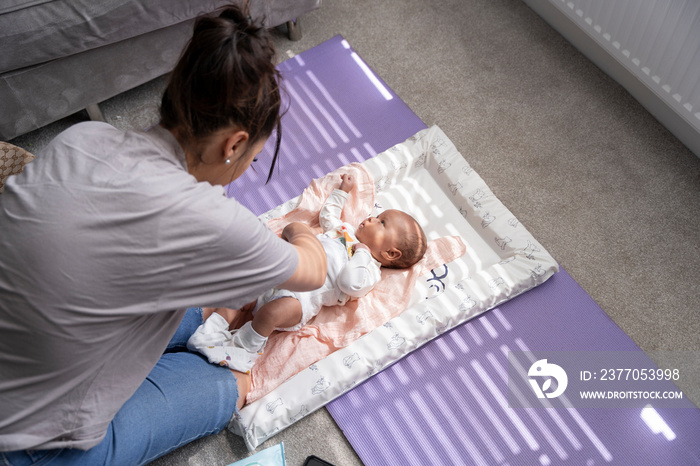 Mother changing diaper to newborn baby girl at home