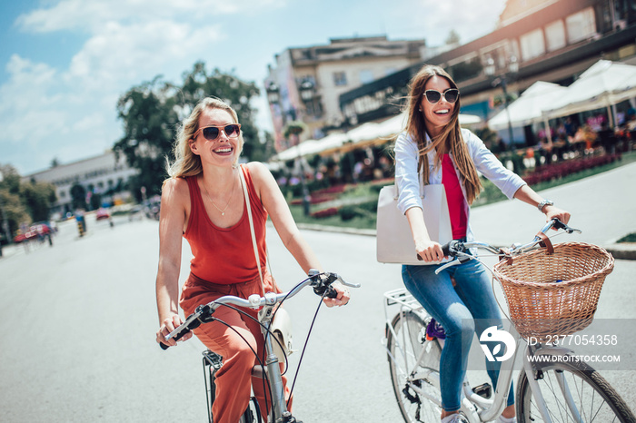 Two beautiful women shopping on bike in the city