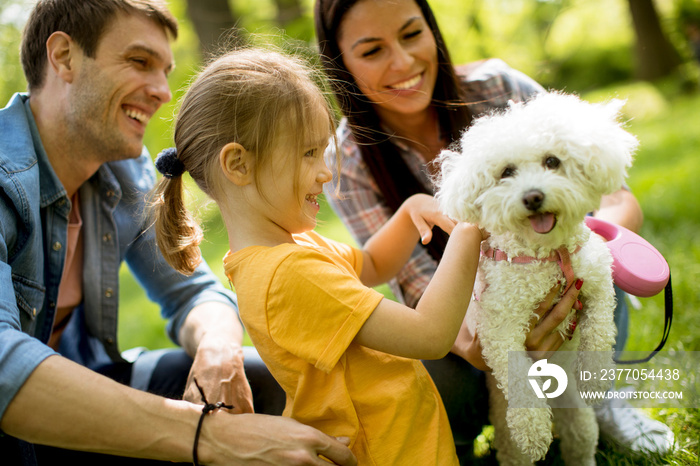 Beautiful happy family is having fun with bishon dog outdoors