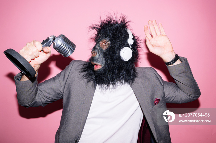 Gesture man with gorilla mask and headphones singing with microphone