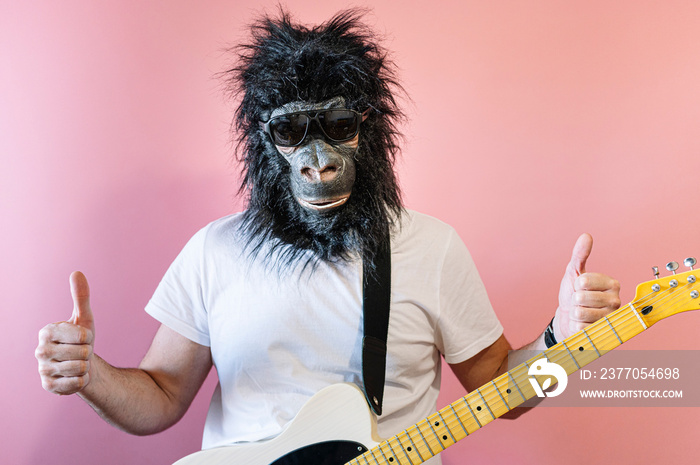 Man with gorilla mask and hanging electric guitar showing his thumbs up