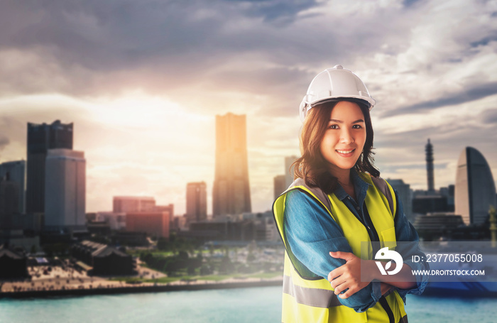 Female Civil engineer with computer and blueprint is standing infront of Japan Yokohama Skyscraper City for city development.