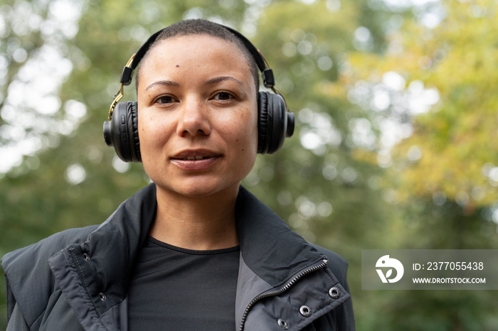 Portrait of smiling woman wearing headphones in park