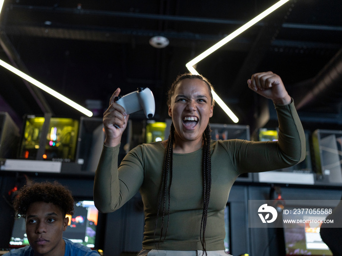 Excited woman playing video games with friends in gaming club