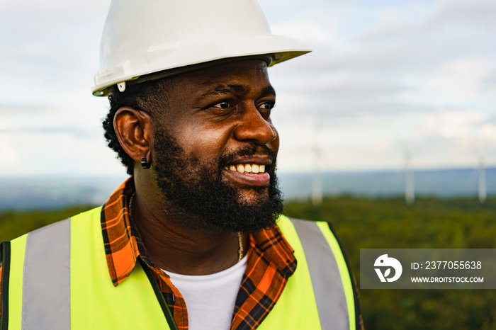 Close up portrait of black optimistic engineer man smiling and looking to the field while working outdoor.