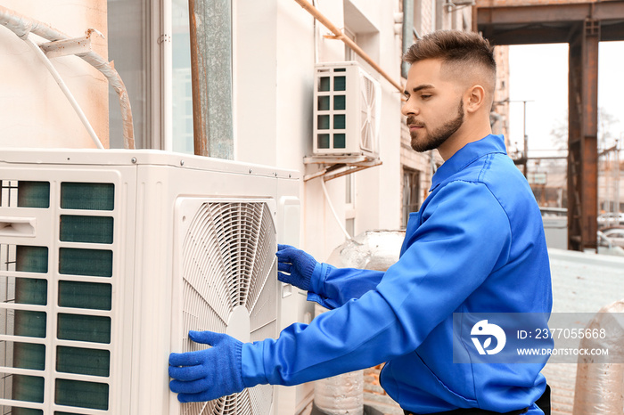 Male technician installing outdoor unit of air conditioner