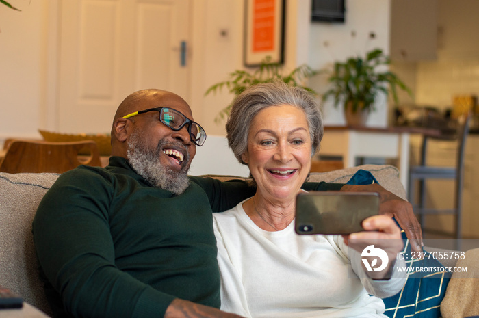 Senior couple using smart phone at home