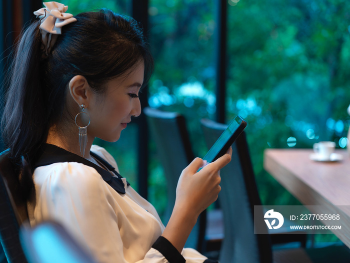 Side view of woman relaxing with smartphone while sitting in conference room