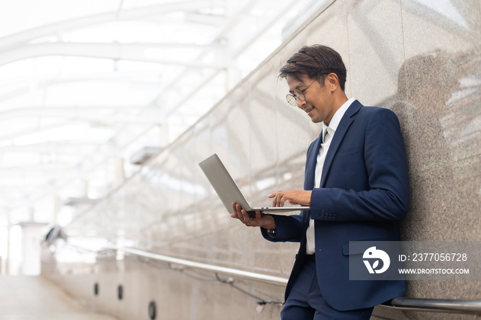 Handsome asian businessman working outdoors with computer