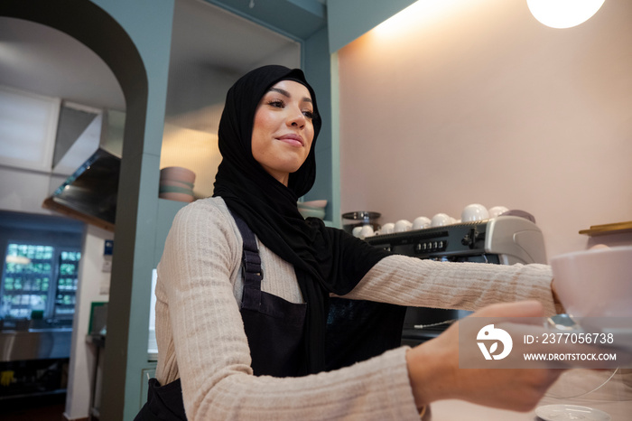 Young woman in hijab working in cafe