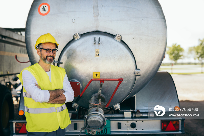 worker standing crossed in front of water truck tank