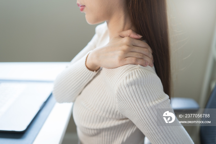 Asian business woman suffering from neck pain working in office sitting at table.