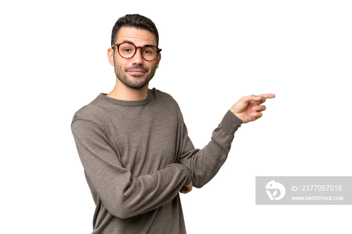 Young handsome caucasian man over isolated background pointing finger to the side