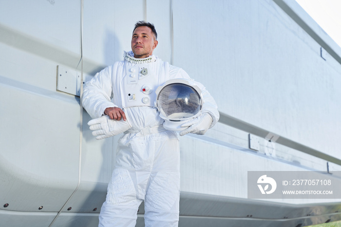 Spaceman in suit holding helmet in hands