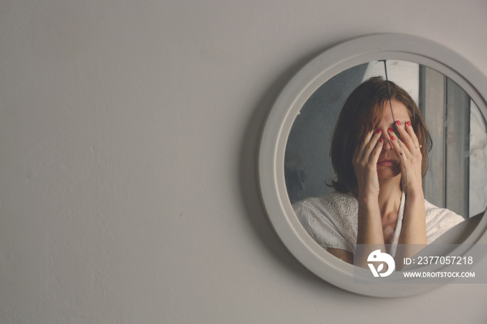 Reflection of a woman’s face in broken mirror. Depression, anxiety, phobia, suicide and mental health concept.