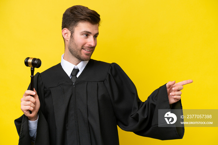 Judge caucasian man isolated on yellow background pointing finger to the side and presenting a product