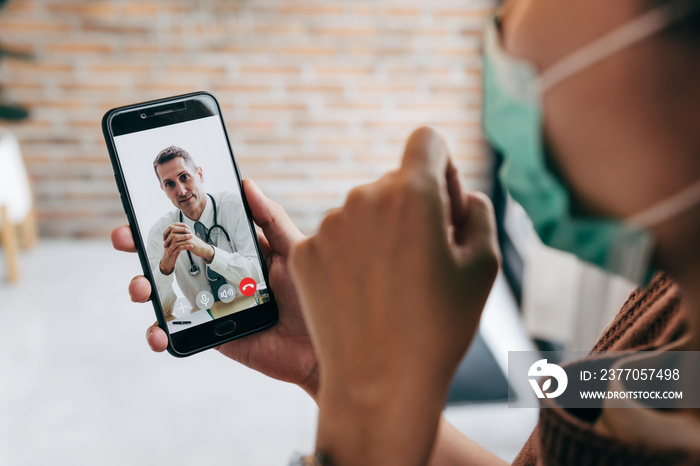 Young woman meet her doctor via video call by smart phone at home, while covid-19 out break.