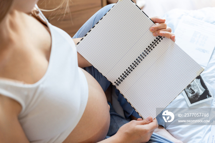 Pregnancy list woman writing. Beautiful pregnant woman writing check list. Happy pregnancy lady holding notepad. Concept maternity, childbirth.