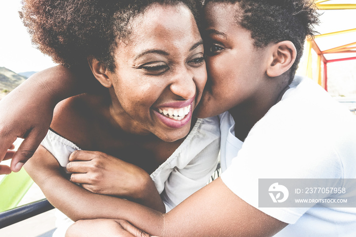 Happy young mother having fun with her child during mum day - Son kissing his mom outdoor - Family lifestyle, motherhood, love and tender moments concept - Focus on faces