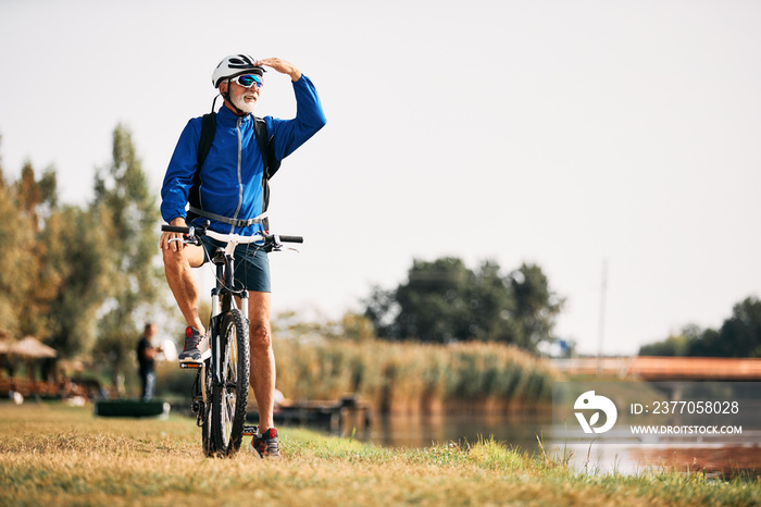 Senior athlete riding bicycle in nature and looking away.