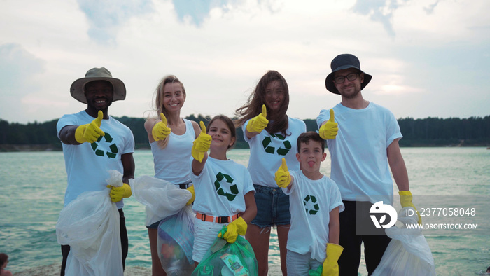 Happy multi-race young people children and adults environment volunteers showing thumbs up supporting ecology and clean nature.