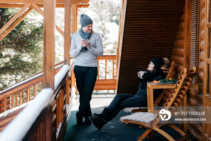 couple of young people a guy and a girl on the porch of a snow-covered wooden house