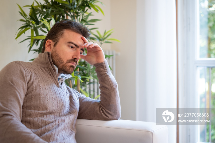 Sad and thoughtful portrait of man alone at home