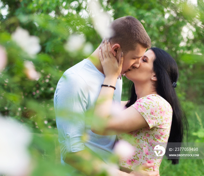 Young teenage couple kissing in the spring nature