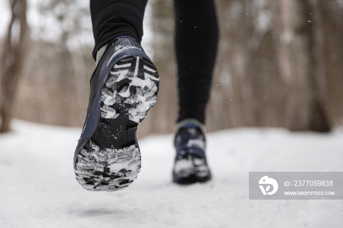 Winter exercise fitness lifestyle athlete walking with running shoes on snow and slippery ice needing traction soles on icy sidewalks. Run outside in cold weather.