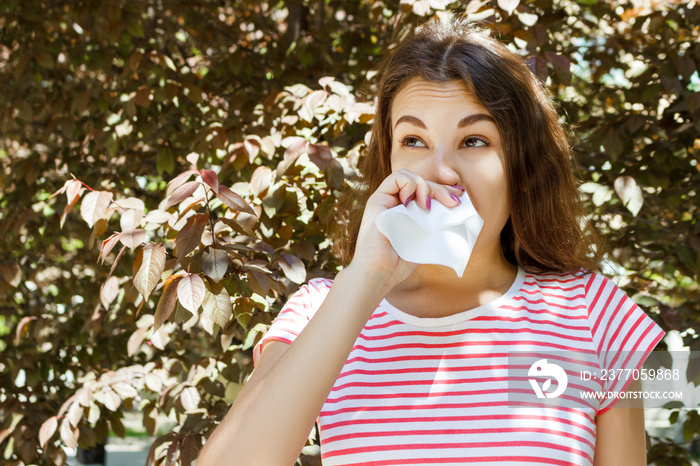 Young girl blowing her nose. Young girl with allergy in autumn park