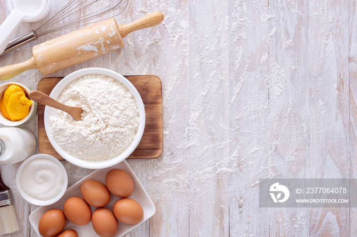 Homemade dough recipe (eggs, flour, milk, sugar) on a wooden table top view.