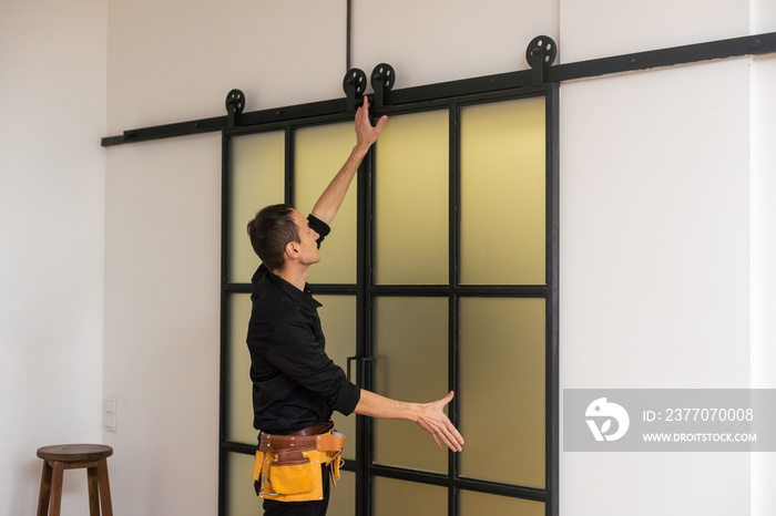 male workers carpenters installing interior glass door with a wooden frame at new luxury apartment.