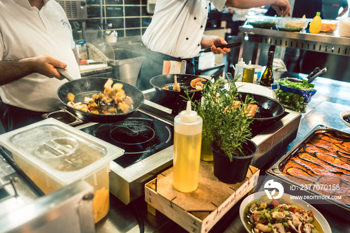 High-angle view of various fresh ingredients on the stove and the counter of a commercial kitchen in a trendy restaurant with fish specialties