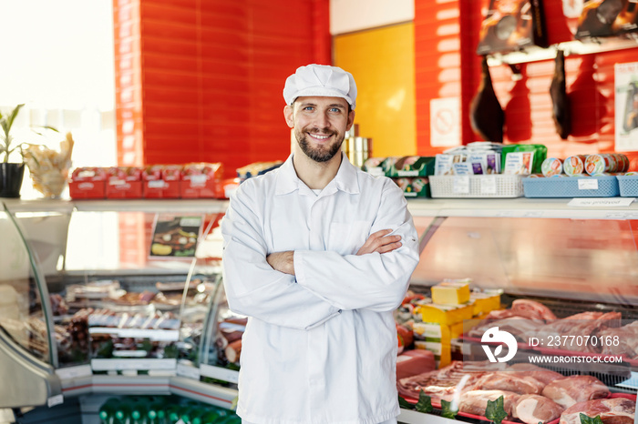 Portrait of successful butcher at butcher shop smiling at the camera.