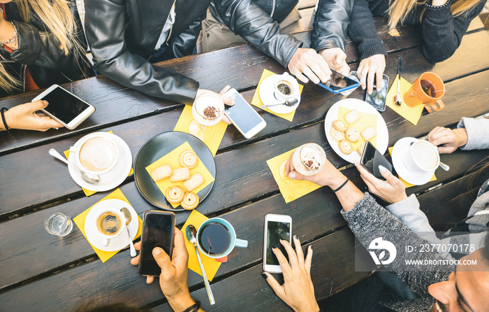 Top view of friends drinking cappuccino at coffee shop restaurant - People having fun together eating cakes and using mobile smart phones at cafe bar - Friendship concept on bright vintage filter